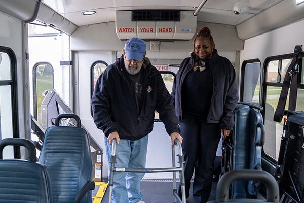 elderly man uses walker as he gets on Access bus