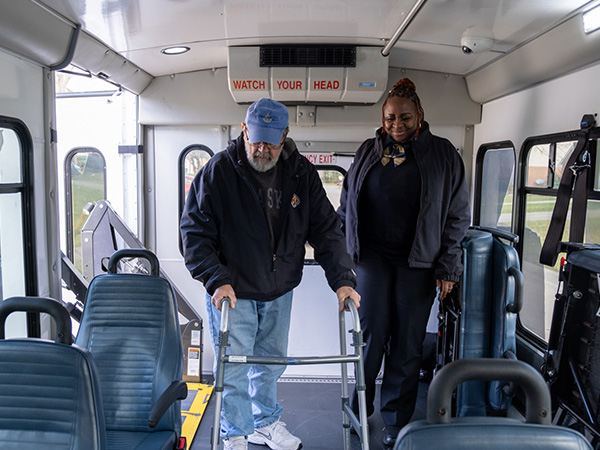 elderly man uses walker as he gets on Access bus