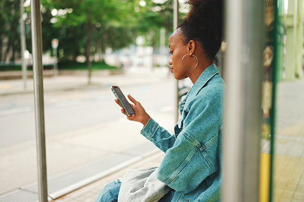 Woman using her mobile phone sitting in the bus stop shelter