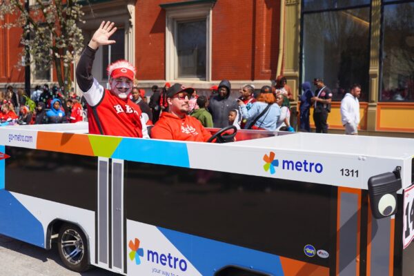 Opening day people drive bus covered cars around