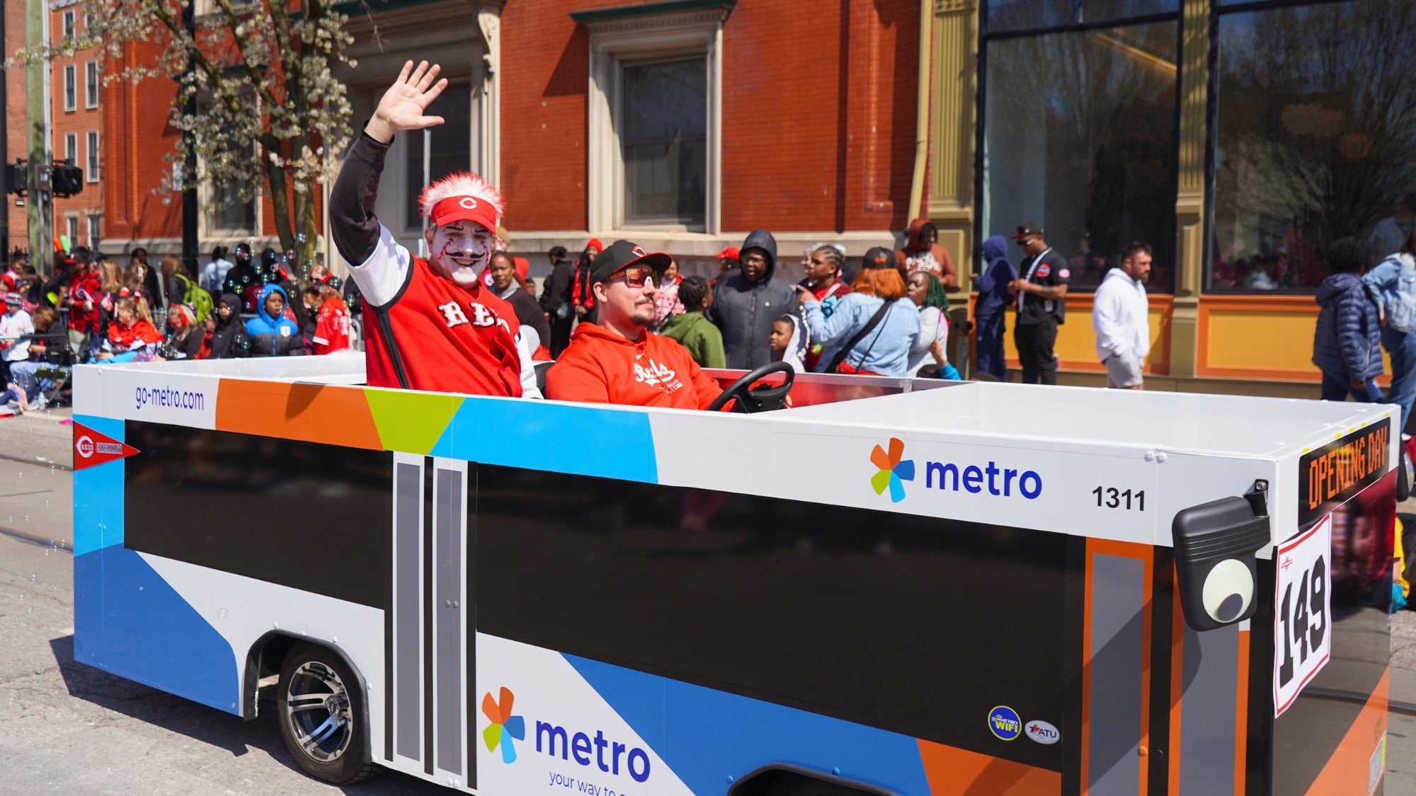 Opening day people drive bus covered cars around