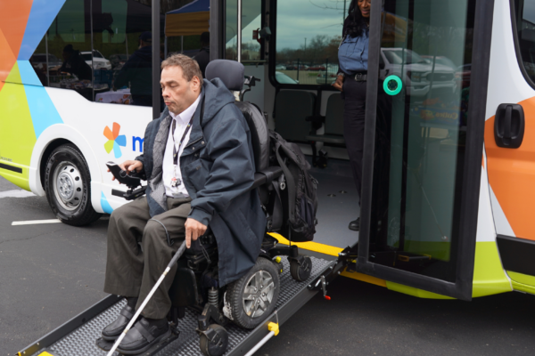 man in wheelchair using ramp to get off accessible bus