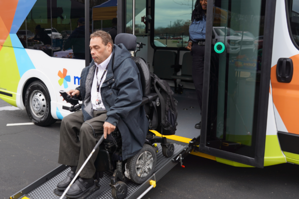 man in wheelchair using bus ramp to get off bus